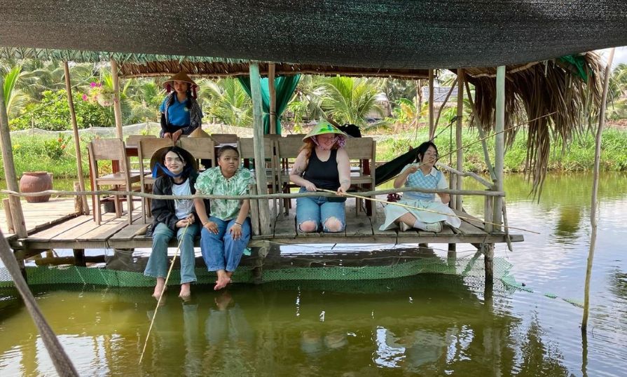Group fishing on a wooden dock in Vietnam during cultural exchange.