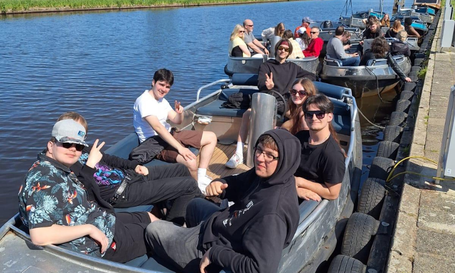 Oliva Digdon and other students are relaxing in small boats docked along a calm canal on a sunny day