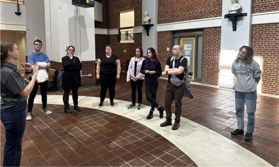 A guide uses ASL to lead a group of students through a tour inside a building at Gallaudet University.