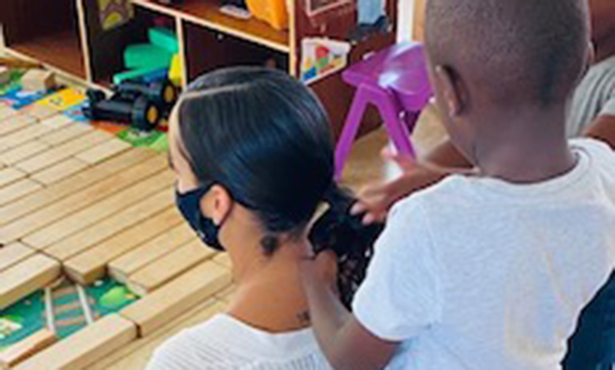 A child fixing Kristen's ponytail