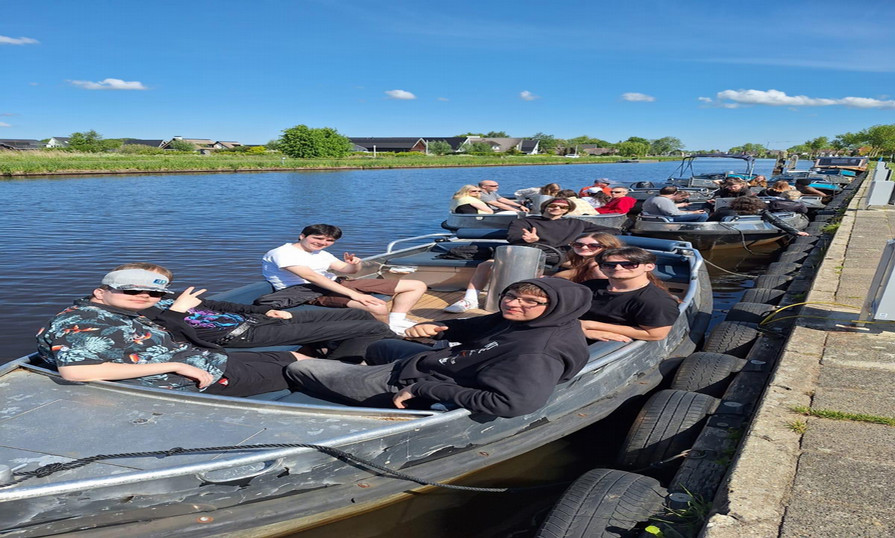 Oliva Digdon and other students are relaxing in small boats docked along a calm canal on a sunny day