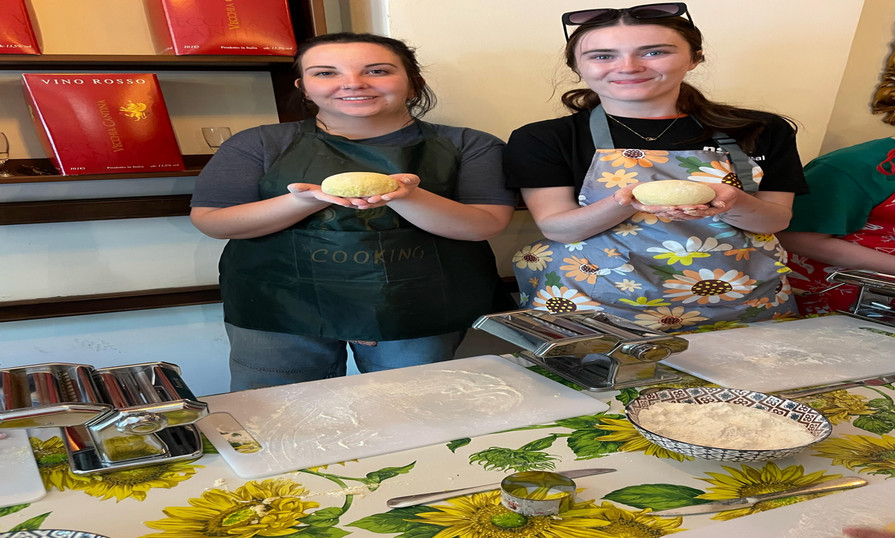 Two students holding pasta dough during a cooking class in Italy