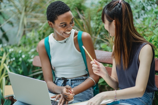 two people sitting together with laptops