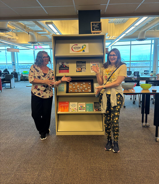 Campus Librarian and work experience student stand in front of book display.