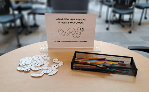 Design your own bookworm bookmark passive programming with bookmarks and coloured pencils on desk. 