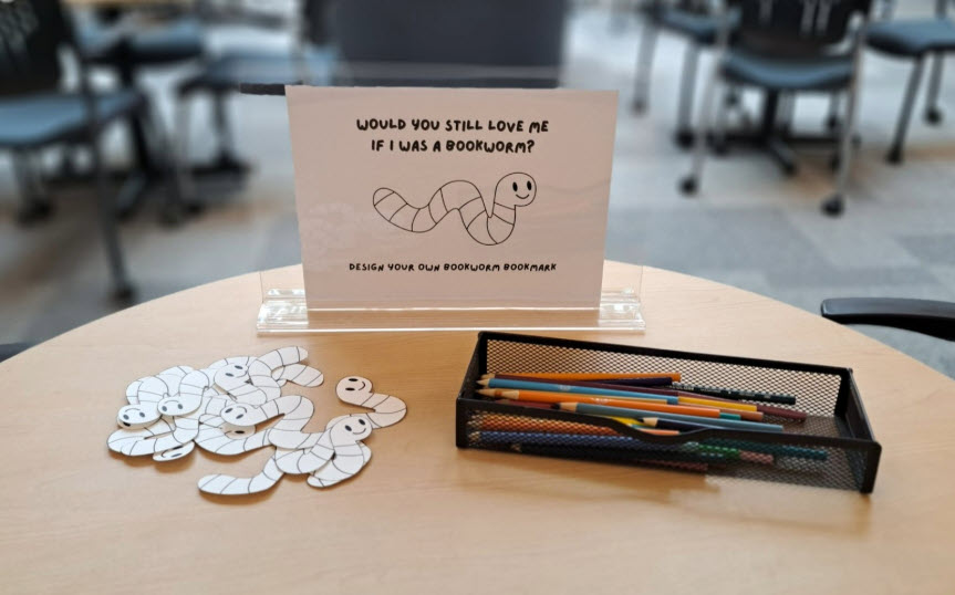 Design your own bookworm bookmark passive programming with bookmarks and coloured pencils on desk. 