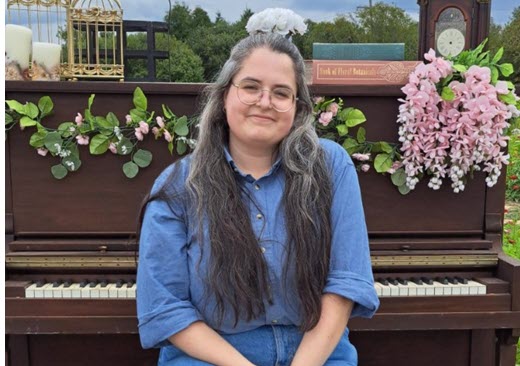 New staff, Erin MacKinnon sitting in front of a piano. 