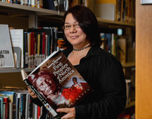 Ricki Lee Christmas holding a library book with the new Indigenous Spine Label.