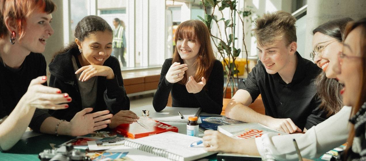 A group of students sit at a table in a common area of an NSCC campus.