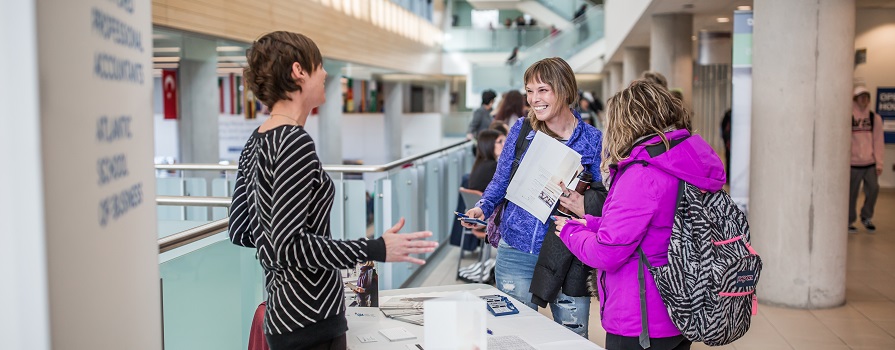 A group of people visiting a booth at NSCC's Open House.